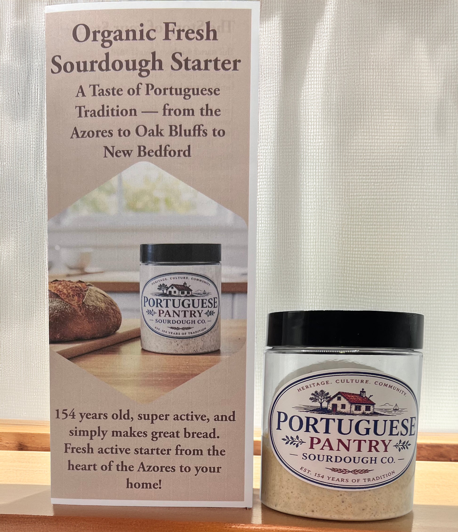 Basil and Bloom sourdough starter jar with promotional sign on a wooden surface.